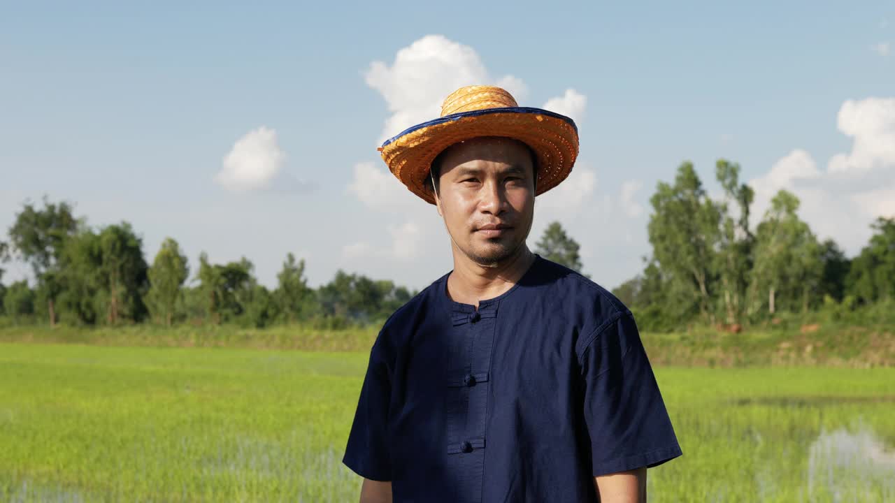 年轻的农民站在稻田里，双臂交叉