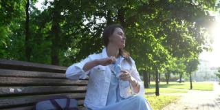 在公园里，一名穿着白色夹克的成年女子在喝瓶装水