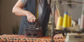近距离拍摄亚洲华人高级妇女裁缝手用传统古玩铁器具在她的工作室熨布
