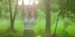 年轻的亚洲女人在花园里练习瑜伽。女性的幸福。模糊的背景。健康的生活方式和放松的观念。年轻的亚洲女孩在公园里做瑜伽。