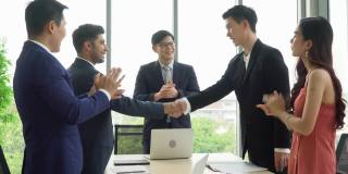 亚洲商务人士会议小组会议在办公室举行。营销团队。老板与客户握手，同事鼓掌或拍手庆祝成功，协议成交
