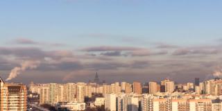 在寒冷的冬日阳光明媚的日子里，一轮满月冉冉升起在莫斯科城市上空。许多建筑物，被傍晚的太阳照明，蓝天和大量的烟雾从火电厂的管道。时间流逝。俯视城市