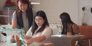 亚洲华人成熟女性裁缝在她的工作室里教她的缝纫班学生缝纫技巧