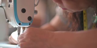 特写亚洲华人女裁缝的手工缝纫过程，在缝纫机上缝纫。