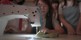 亚洲华人高级妇女裁缝教学展示她的学生在缝纫课在工作室工作坊