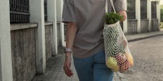 女人带着网眼线编织的购物袋走在外面