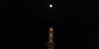 月亮在夜晚的河流或海洋的路径。月光映在水面上。黑色背景