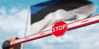 在爱沙尼亚国旗前打开了有停止标志的路障