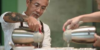 专业亚洲华人高级男咖啡师品级员将热水倒入陶瓷咖啡杯中，准备拔杯咖啡品质测试