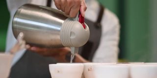 近距离观看专业亚洲华人咖啡师将热水倒入陶瓷咖啡杯中准备拔杯咖啡品质测试