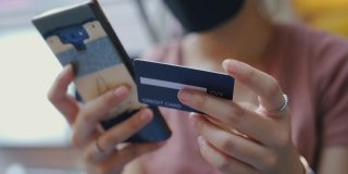 亚洲女性使用手机进行信用卡在线交易。