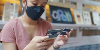 亚洲女性使用手机进行信用卡在线交易。