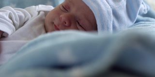新生儿的脸肖像早期的日子在宏观睡眠和睁开眼睛在蓝星背景。《帽子上生命开始的几分钟》中的孩子。婴儿，分娩，出生的最初时刻，开始的概念