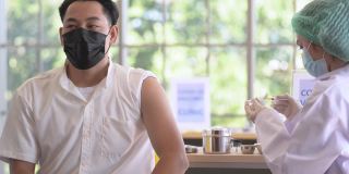 在大流行期间，年轻的亚洲男性患者正在给护士注射预防Covid - 19感染的疫苗。为基本人的社会生活接种疫苗。疫苗和covid-19疫情概念