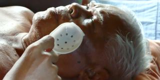 孙子用塑料保护罩盖住了一位亚洲老人的眼睛