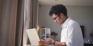 年轻的亚洲商人坐在家里的客厅里用智能手机