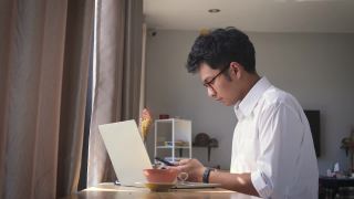 年轻的亚洲商人坐在家里的客厅里用智能手机视频素材模板下载