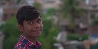一名印度少年的肖像，一边盯着镜头一边微笑。上学的青少年对着镜头微笑。积极情绪