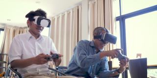 快乐的亚洲老人和他成年的儿子在家里的客厅戴着虚拟现实眼镜一起玩电子游戏