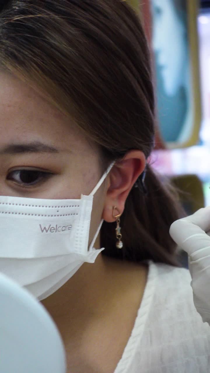 美容院，美容师为年轻少女做耳洞手术