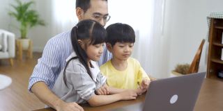 亚洲孩子在家和父亲一起上网络课程。