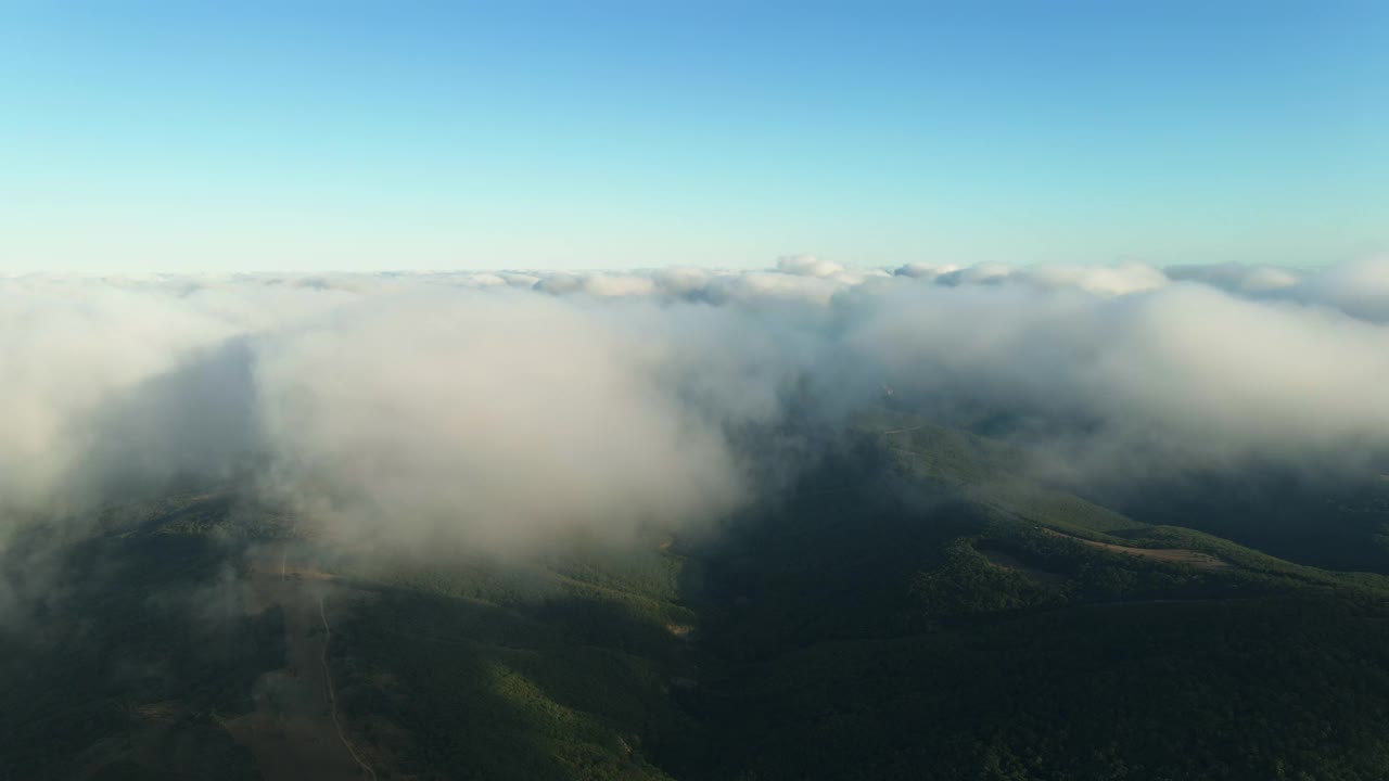 移动的白云蓝天上的海岸线和海面风景鸟瞰。无人机在蔚蓝的天空中飞过松软的云朵，在海边的全景图上向前飞。太阳是隐藏的。雾。戏剧性的