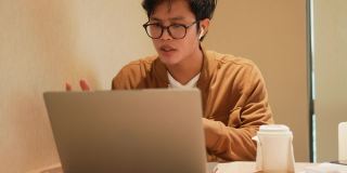 亚洲年轻员工男子通过数码平板电脑视频通话的慢镜头，与合作伙伴商议项目计划，对商业技术和新常态生活理念有新的想法