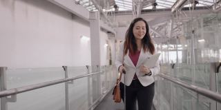 女商人在机场往前走，亚洲女商人，带着行李、背包和笔记本电脑，在机场步行去上班，感受新旅程的积极情绪，手持前视