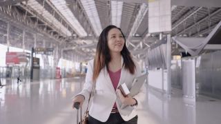 亚洲女商人在机场，去做生意，在机场工作带着行李，手持式跟随头部拍摄正面视图视频素材模板下载