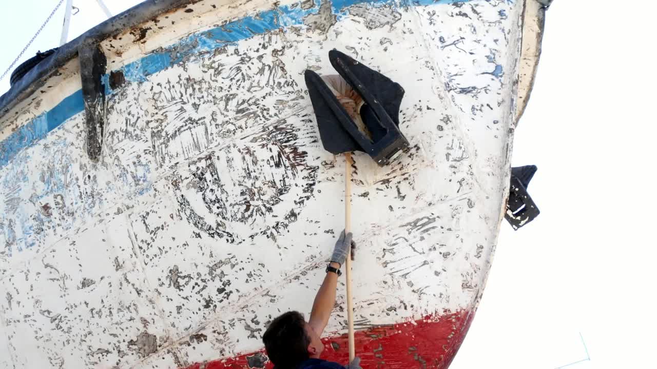 在港口的造船厂，工人给生锈的旧船涂上底漆。