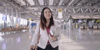 亚洲女商人在机场，去做生意，在机场工作带着行李，低角度慢动作手持式跟随前视图