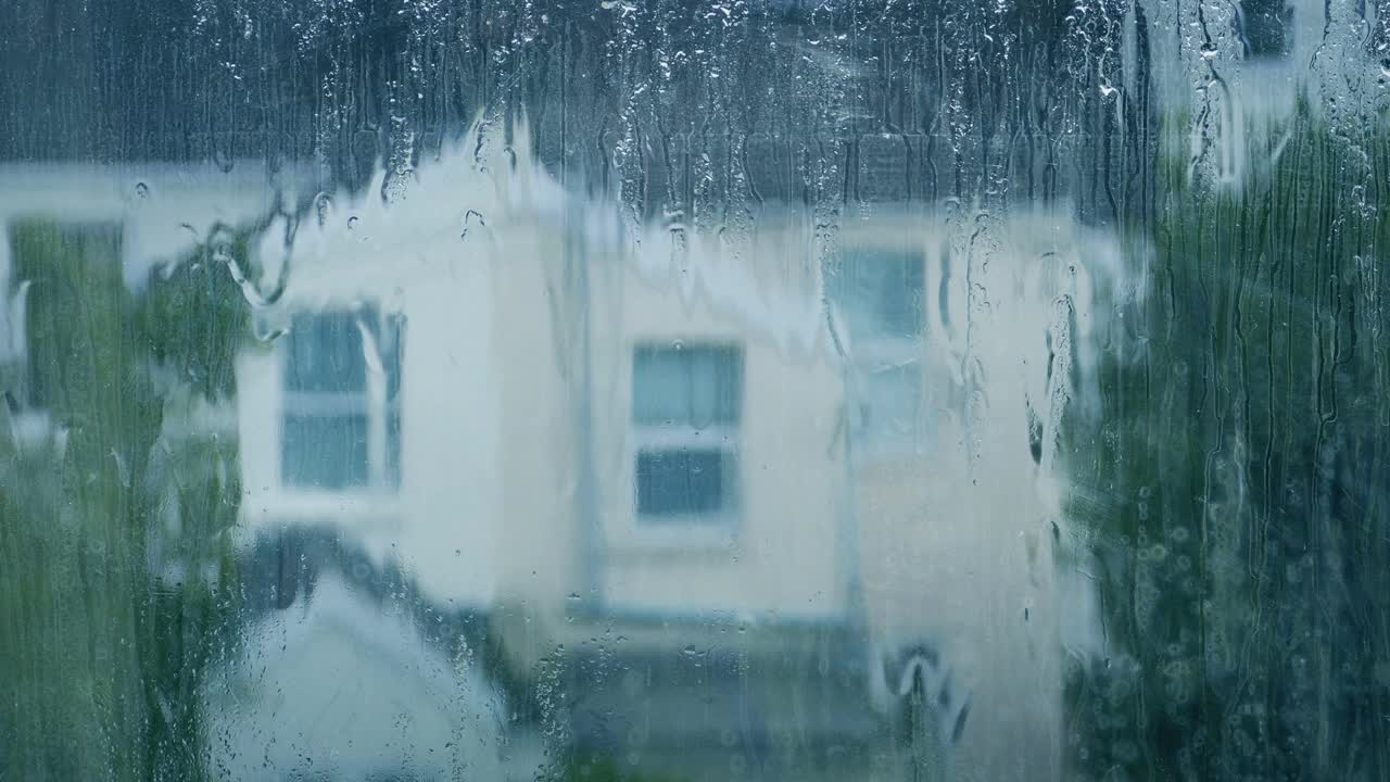 雨从窗户上落下，背景是房子