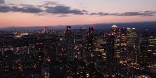 夜城的空中全景画面。高大的现代化办公大楼，日落后窗户有灯光。英国伦敦