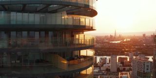 拉回未来圆柱形公寓建筑Arena Tower的镜头，背景是日落的天空。英国伦敦