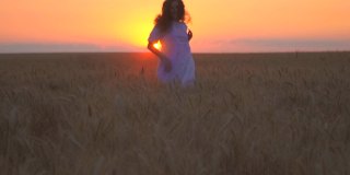 一个漂亮的白人女人在战场上奔跑。这个女孩在尽情地跳舞。大自然母亲。享受日落。地平线上的太阳是金色的。