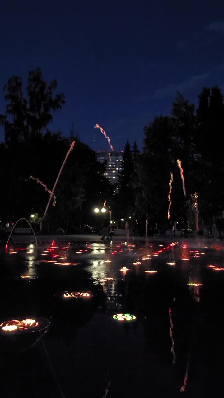 五彩缤纷的灯光音乐舞蹈城市喷泉。喷泉的碎片。明确coporful水。以公园为背景。晚上的时间。垂直新西伯利亚