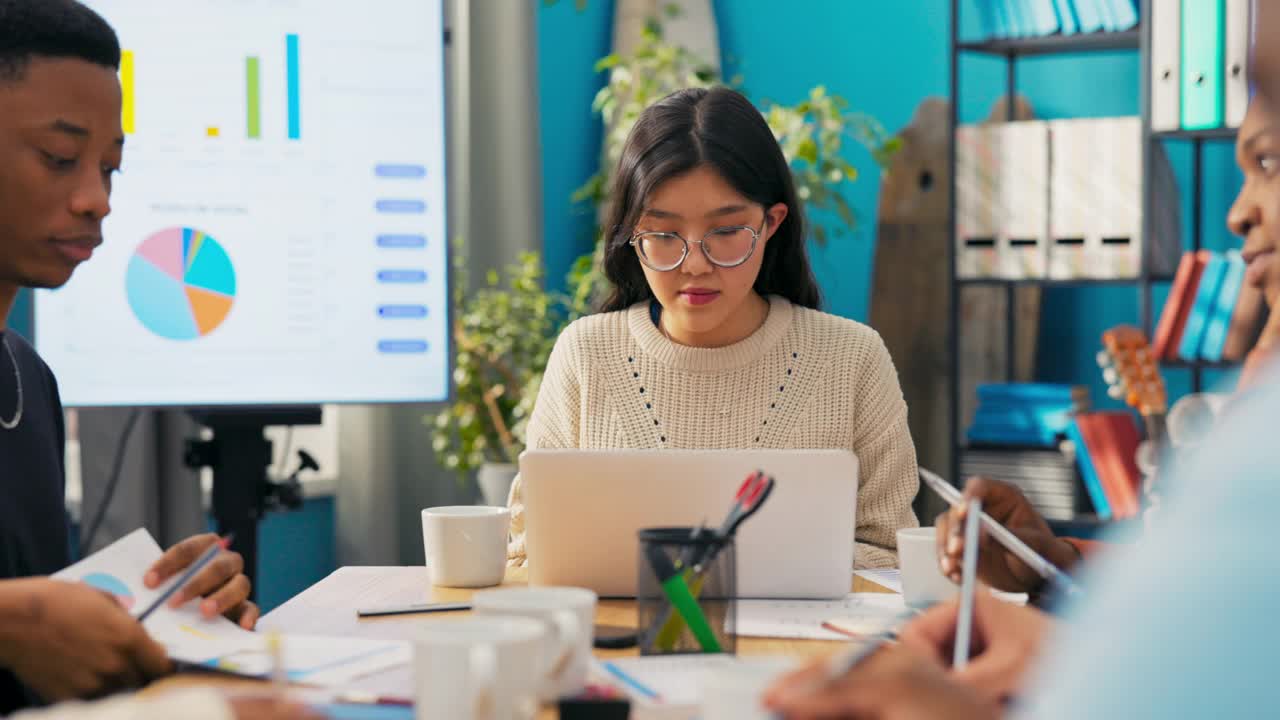 特写女孩的脸，谦卑的办公室职员，女人写电子邮件，发送信息，做报告，文件在笔记本电脑，旁边的工作朋友准备时间表，公司估计