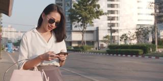 亚洲女商人穿着时尚的办公室服装，在公路上打车，拿着智能手机，站在城市现代城市的户外。