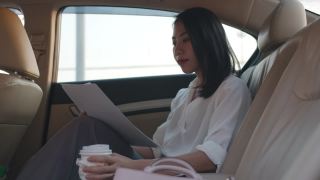 亚洲女商人在时尚的办公室服装工作和喝一次性纸杯热饮在都市现代城市的汽车后座的早晨。视频素材模板下载