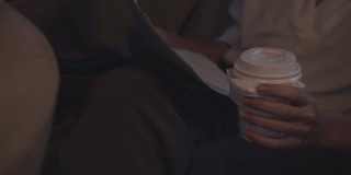 亚洲女商人在时尚的办公室服装工作和喝一次性纸杯热饮在都市现代城市的汽车后座的早晨。