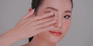 一个女孩在脸上涂保湿霜的肖像。亚洲年轻女性美丽的脸，自然的皮肤。