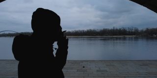 路堤上一个年轻人在黑暗中抽烟的剪影。