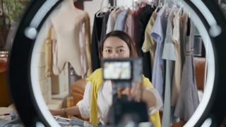 亚洲妇女有直播评论产品和谈话摄像机现场录制视频在家里的客厅。视频素材模板下载