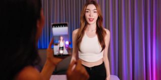 亚洲混血女性网红在手机社交媒体上拍摄舞蹈视频，在家玩乐。分享视频到社交媒体应用程序。