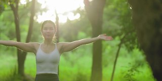 年轻的亚洲女人在花园里练习瑜伽。女性的幸福。模糊的背景。健康的生活方式和放松的观念。年轻的亚洲女孩在公园里做瑜伽。