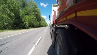 在穿越森林的公路上，一辆半卡车正开着，载着货物视频素材模板下载