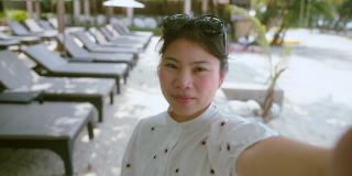 亚洲女性旅行者穿着休闲布衣享受假期日落时刻手用智能手机设备社交媒体交流。亚洲女性喜欢周末在海滩日落时间旅行。
