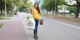 一名妇女将蔬菜和水果放入水果袋，并在可重复使用的袋子上写着“不再使用塑料”