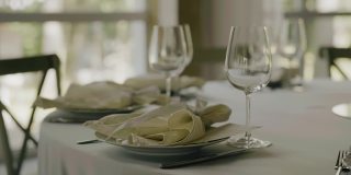 在白色桌布上的桌子上有餐具和一个玻璃杯。盘子已经洗干净，可以上菜了