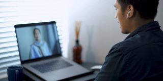 一名亚洲男子在家庭办公室用笔记本电脑与客户视频通话。